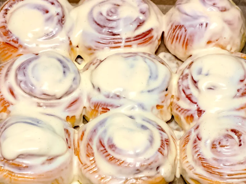 Nine golden glazed cinnamon rolls in a baking tray