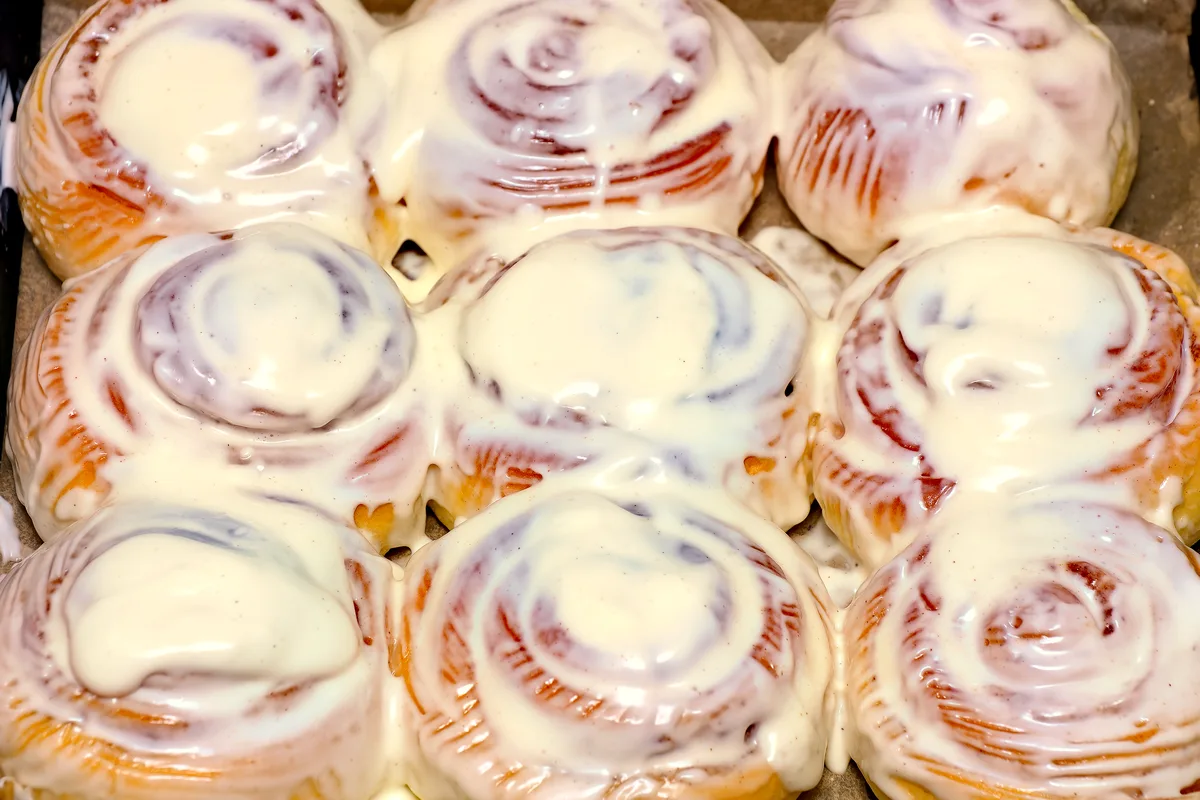 Nine golden glazed cinnamon rolls in a baking tray