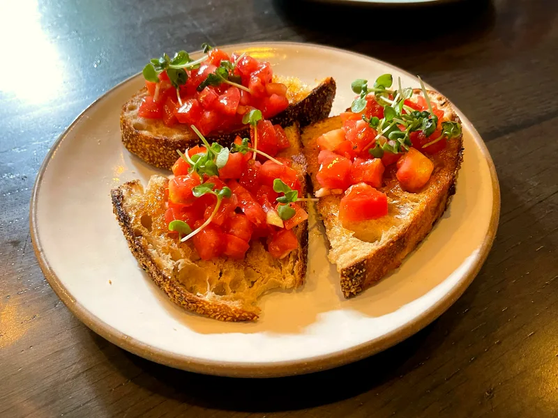 Plate of easy tomato bruschetta with grilled sourdough slices topped with diced marinated tomatoes and fresh herbs