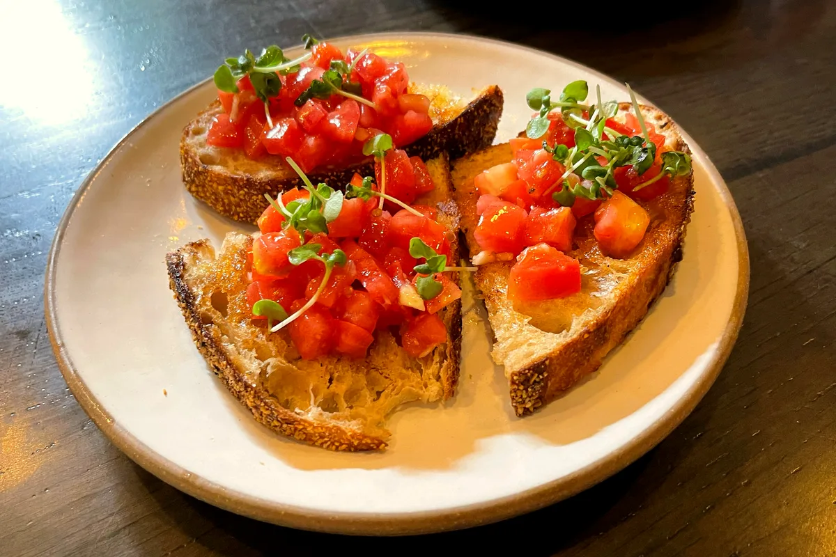 Plate of easy tomato bruschetta with grilled sourdough slices topped with diced marinated tomatoes and fresh herbs