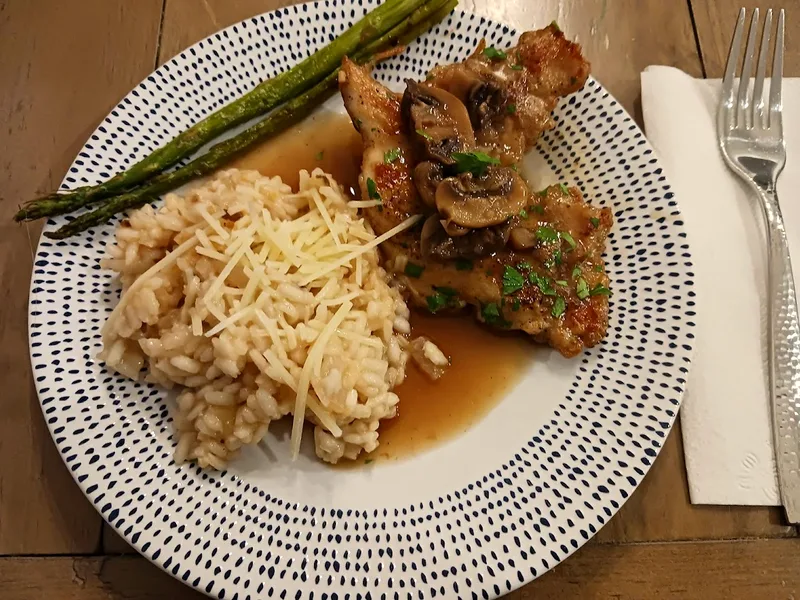 Chicken marsala cutlets topped with mushrooms in brown marsala sauce, served with risotto and asparagus