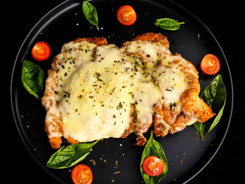 Easy chicken parmesan topped with melted cheese, cherry tomatoes and basil
