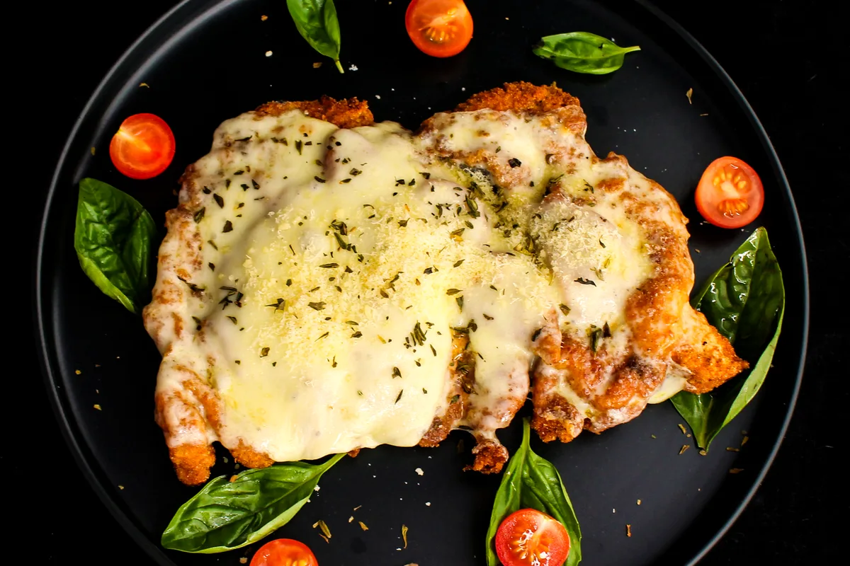 Easy chicken parmesan topped with melted cheese, cherry tomatoes and basil