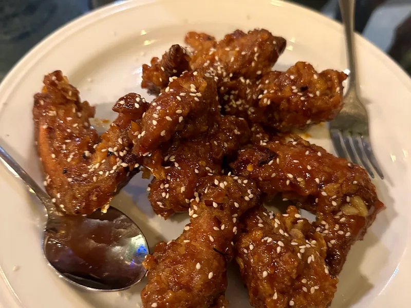A plate of crispy golden-brown chicken wings garnished with sesame seeds