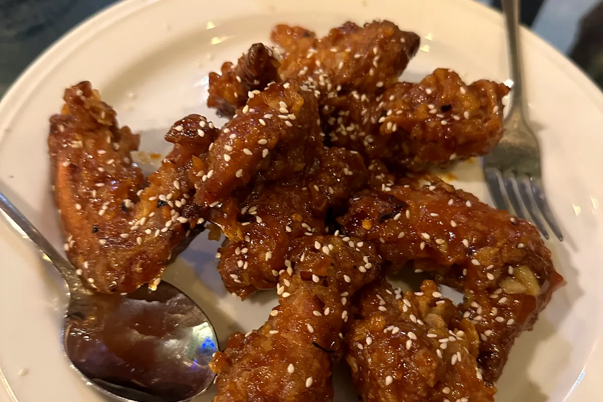 A plate of crispy golden-brown chicken wings garnished with sesame seeds