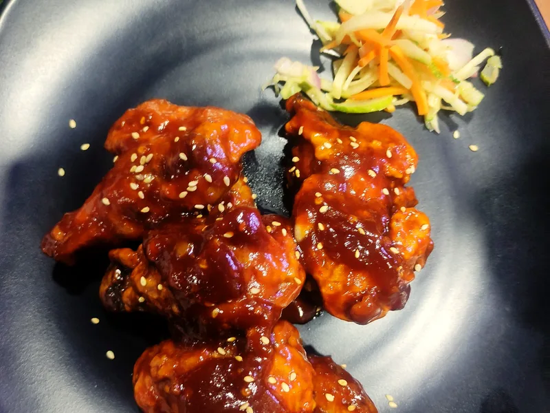 Air fryer honey garlic chicken bites with glossy sticky glaze, sesame seeds and green onions
