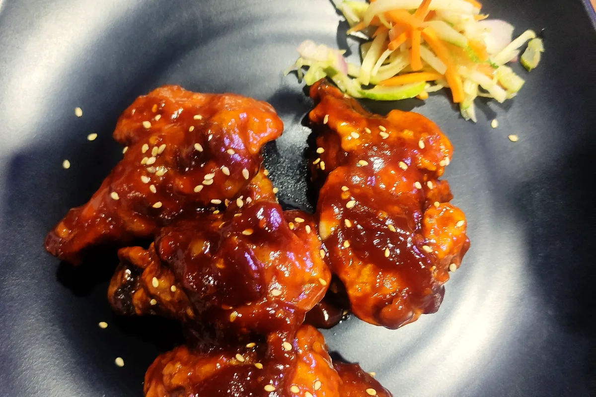 Air fryer honey garlic chicken bites with glossy sticky glaze, sesame seeds and green onions