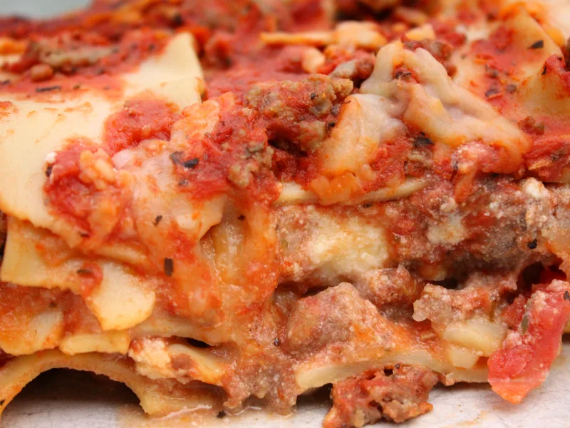 Close-up slice of beef lasagna showing layers of pasta, rich meat sauce and melted cheese