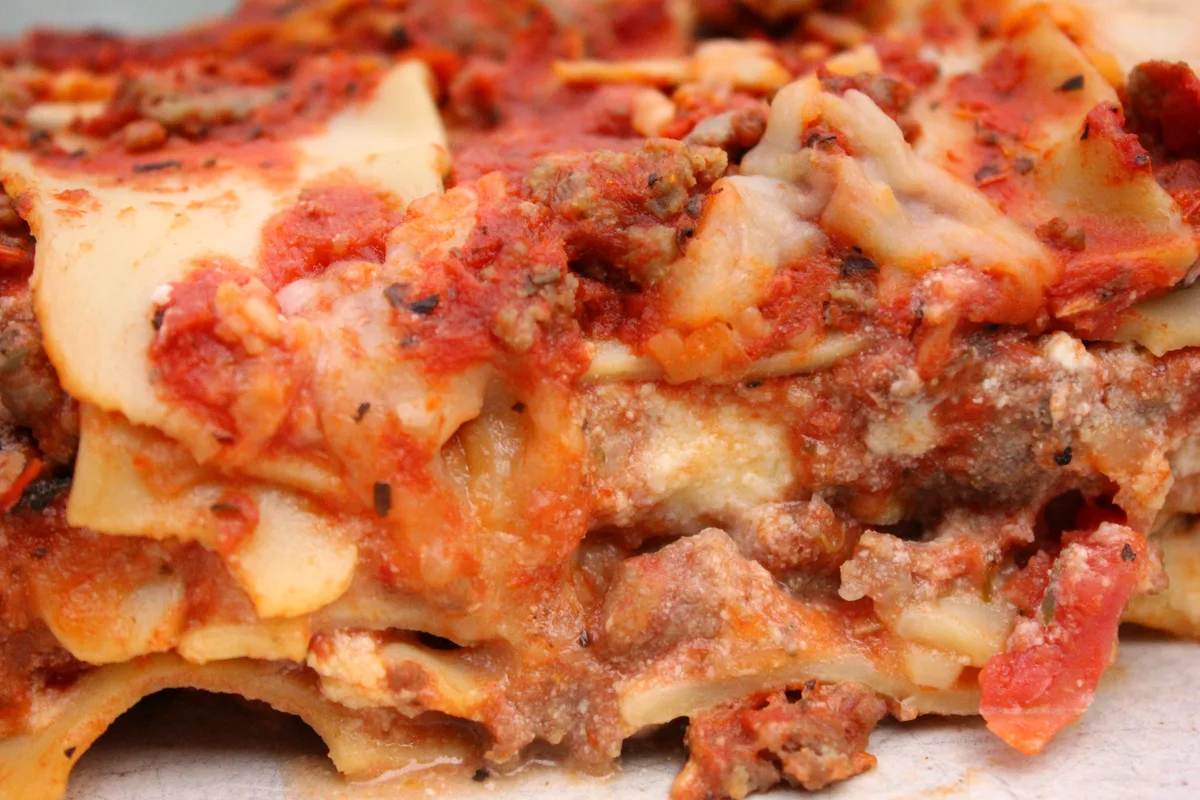 Close-up slice of beef lasagna showing layers of pasta, rich meat sauce and melted cheese