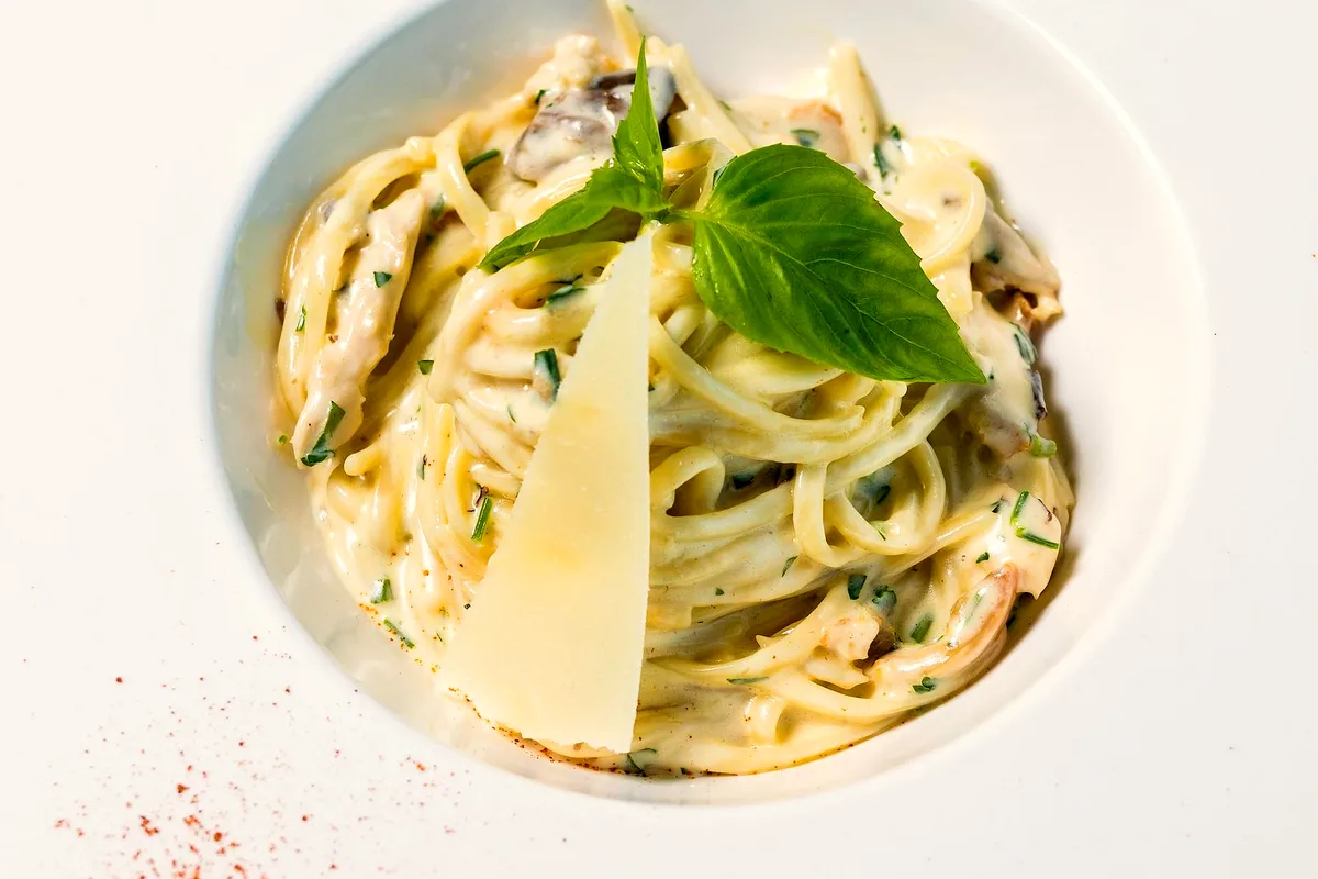 Creamy garlic Parmesan pasta in a pan with fresh herbs and grated cheese