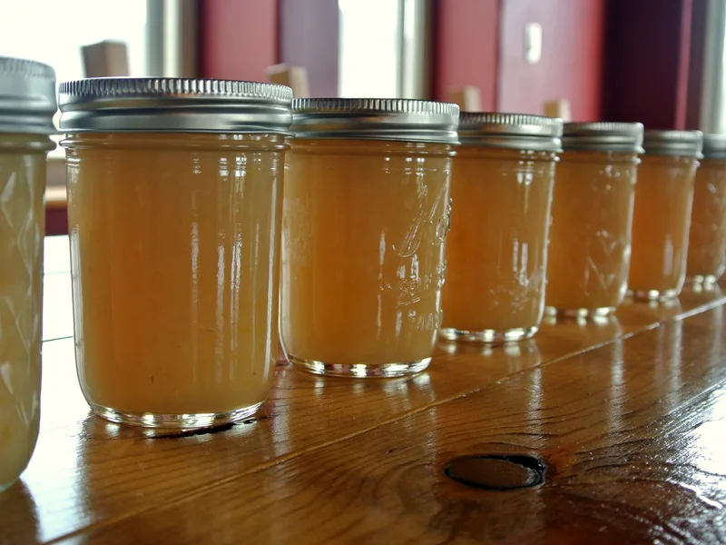 Easy spiced pear preserves in half-pint canning jars with fresh pears, cinnamon sticks and star anise beside them
