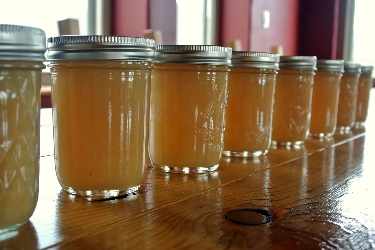 Easy spiced pear preserves in half-pint canning jars with fresh pears, cinnamon sticks and star anise beside them