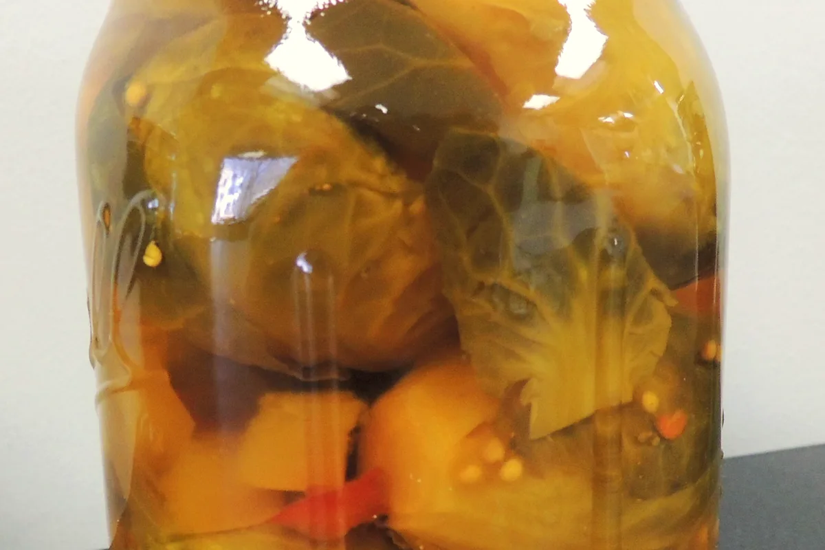 Mason jar of pickled Brussels sprouts in golden brine with mustard seeds and red pepper