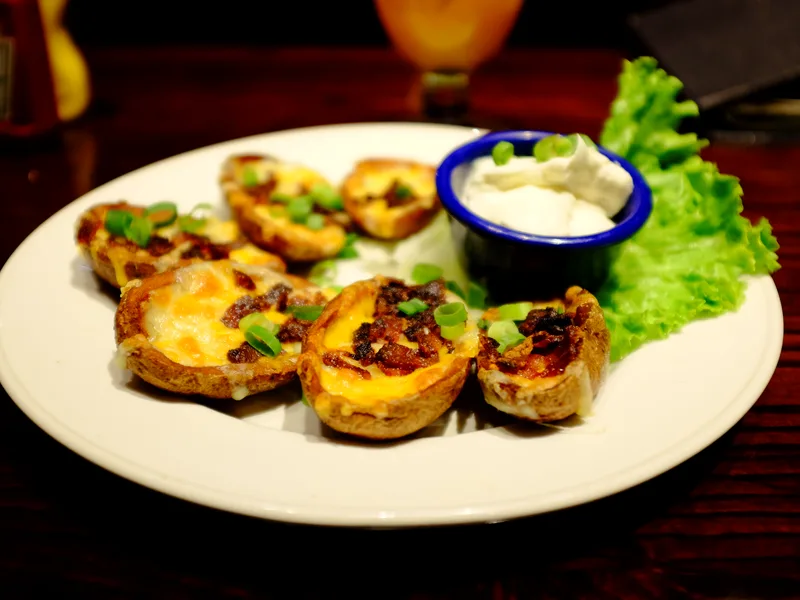 Crispy air fryer potato skins loaded with melted cheddar, bacon bits and scallions, with sour cream for dipping