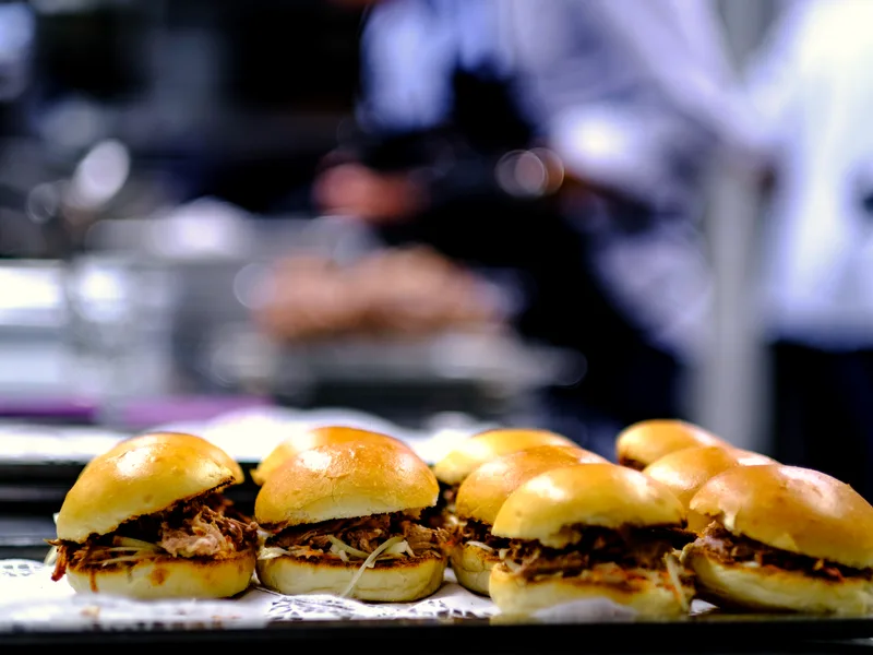 Tray of pulled pork sandwiches on soft buns filled with shredded slow-cooked pork