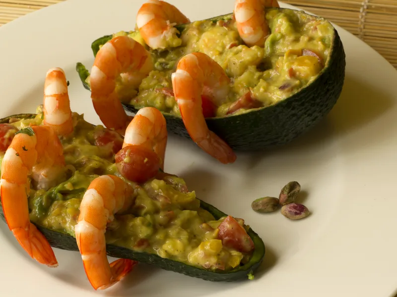 Avocado halves stuffed with shrimp salad, arranged on a plate with lime wedges and cherry tomatoes
