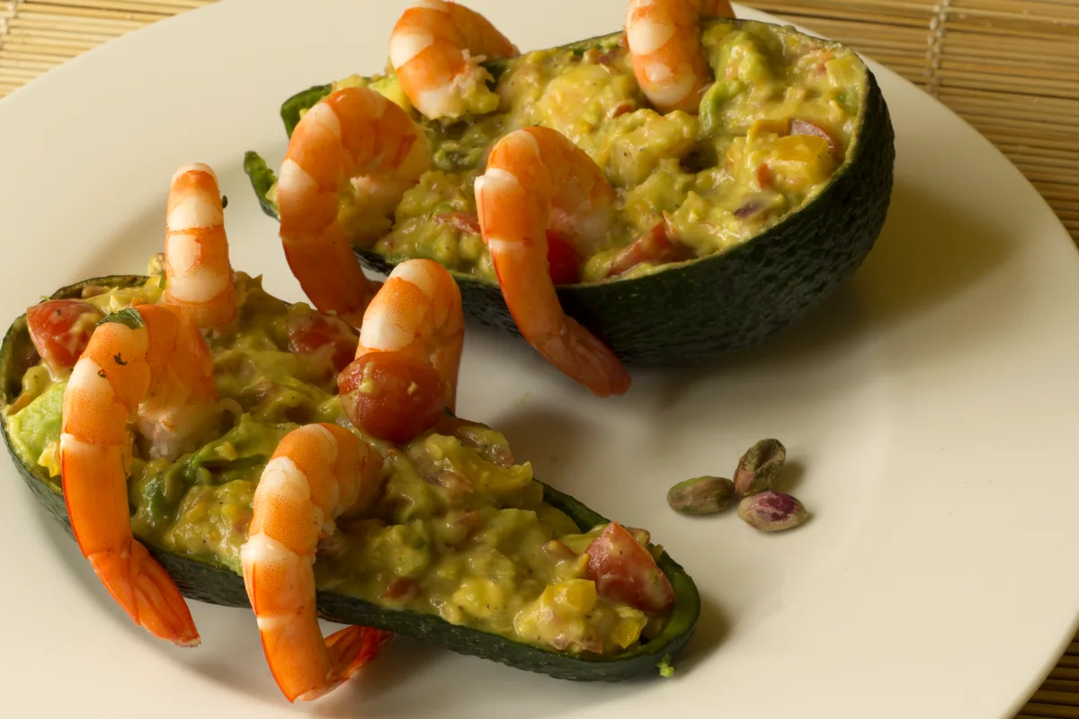 Avocado halves stuffed with shrimp salad, arranged on a plate with lime wedges and cherry tomatoes