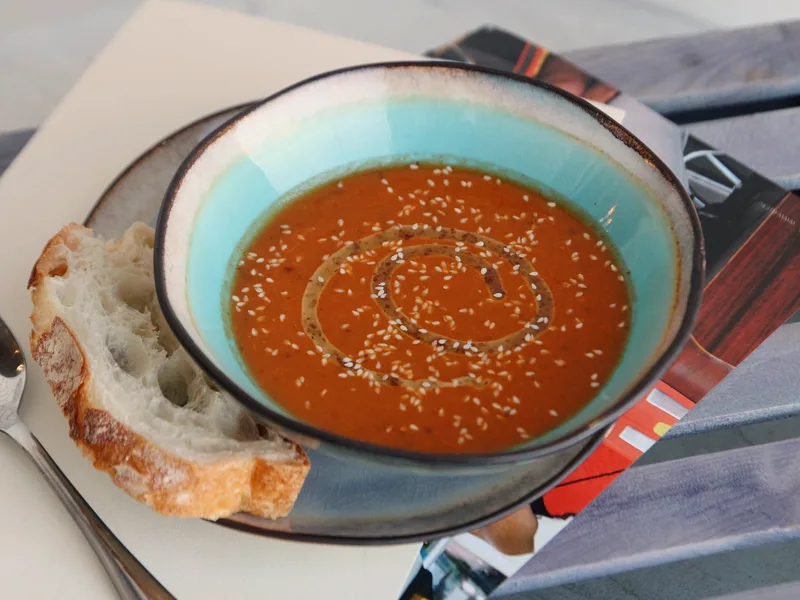 Creamy tomato tortellini soup in a bowl with spinach, basil and a swirl of cream