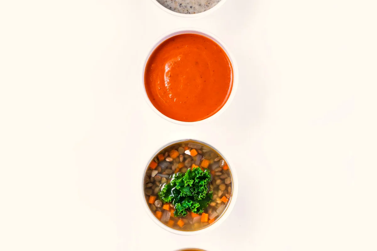 Homemade vegetable soup for canning with carrots, potatoes and jars of preserved soup